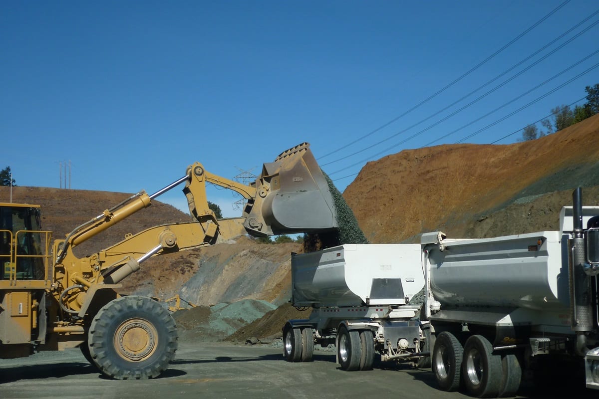 A large dump truck is parked next to a trailer.