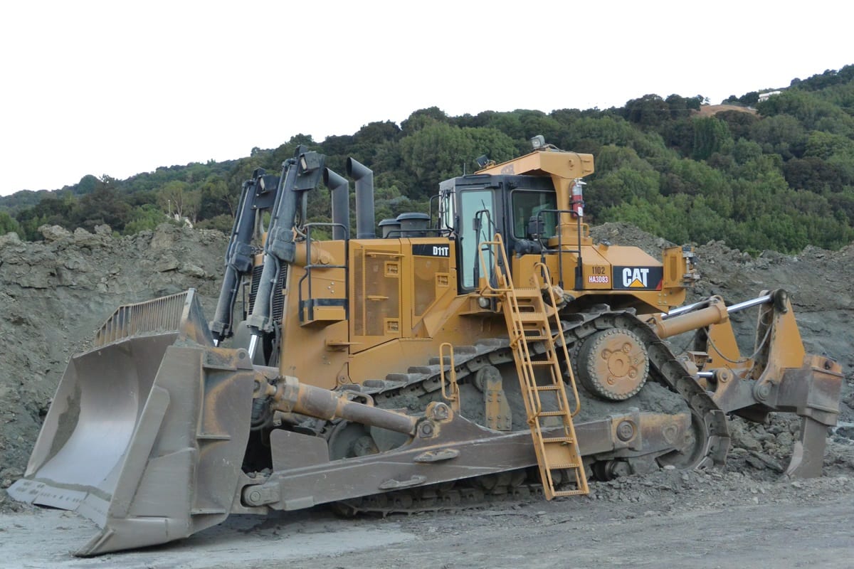 A large yellow bulldozer parked on top of a hill.